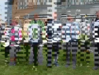 collection of people holding up paper numbers to make 150000