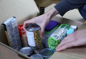 hands placing a tin into a box of a collection of food