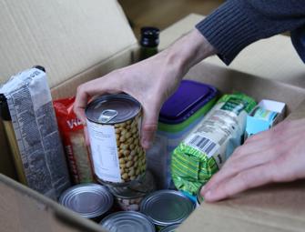 hands placing a tin into a box of a collection of food