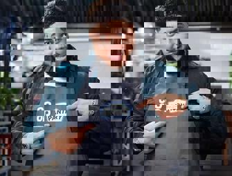 Big Zuu in a grey apron pointing to the your local pantry logo