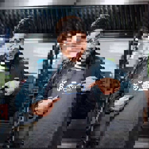 big zuu with a co-op and your local pantry apron, pointing to the logo