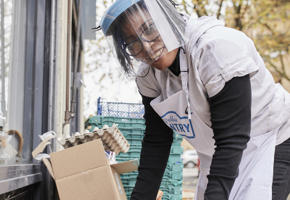 Woman with plastic mask putting eggs inside a box 