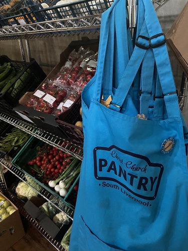 Pantry apron hanging from shelves holding fresh fruit and veg