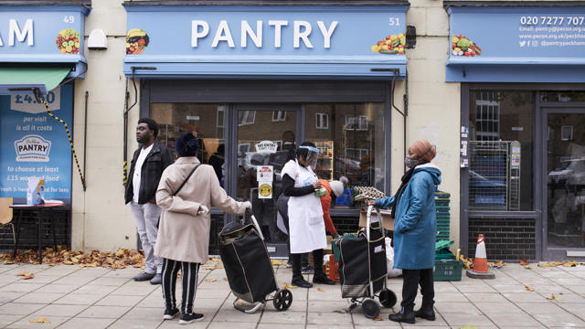 woman with shopping baskets in front of blue pantry sign shop
