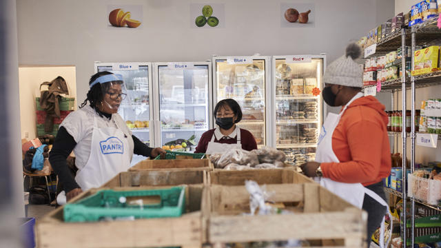 Wooden storage in front of people sorting through food