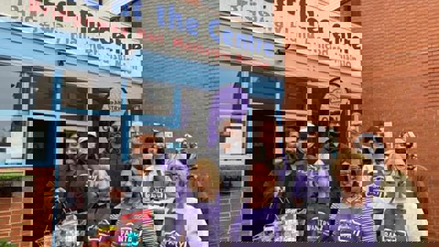 group in purple aprons in front of pantry entrance 