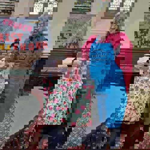 woman sitting in chair holding up bag with pantry worker in blue apron