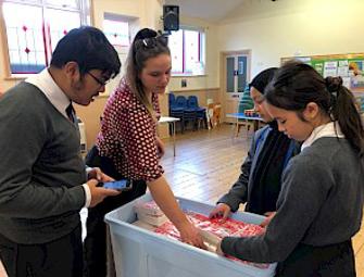 Children inn school uniforms inside a hall picking out food