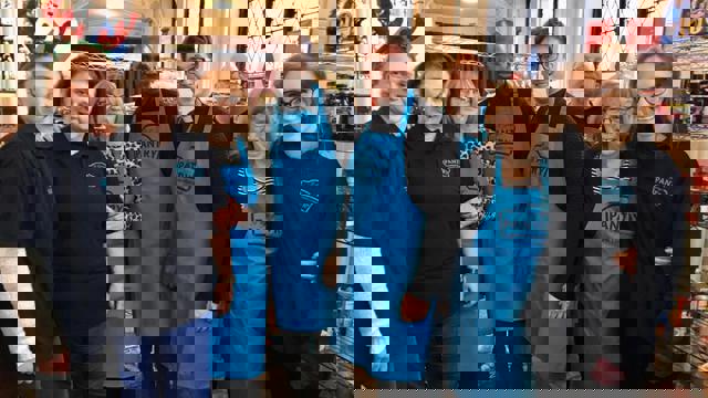 group of people in black shirts and blue aprons