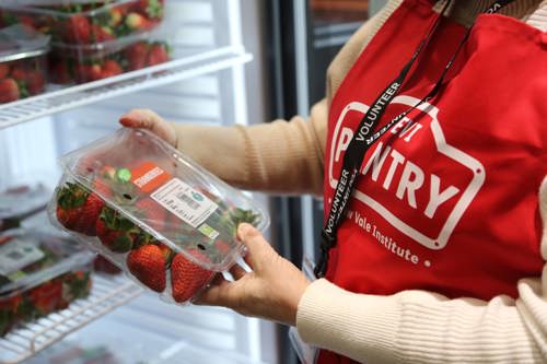 Lady in an apron looking at strawberries in a fridge