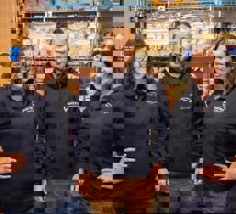 two woman and one man in front of a food pantry