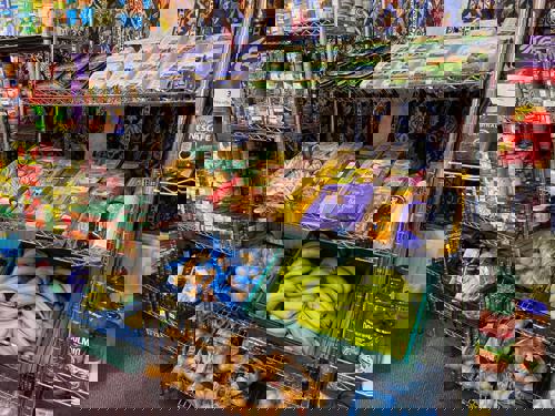 Shelves packed with packet and canned food, bananas and potatoes