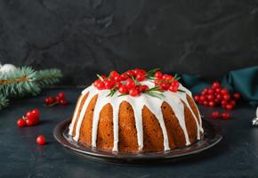 close up of Christmas Cake on a black table topped with red berries