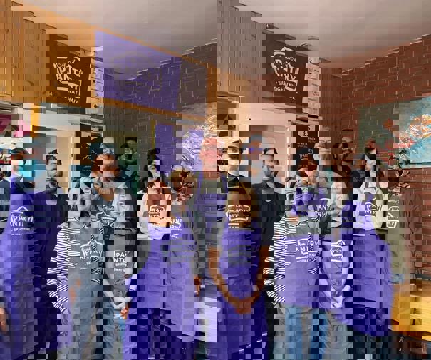 Group of pantry volunteers in purple aprons inside meadows pantry