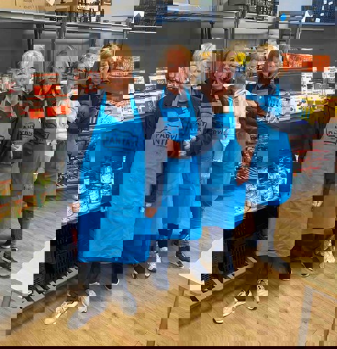 4 woman in blue aprons in a pantry room
