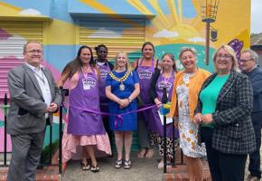 mayor and pantry volunteers in purple aprons next to a ribbon for opening event