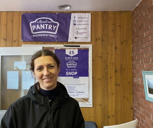 Woman smiling with meadows pantry logo sign behind her