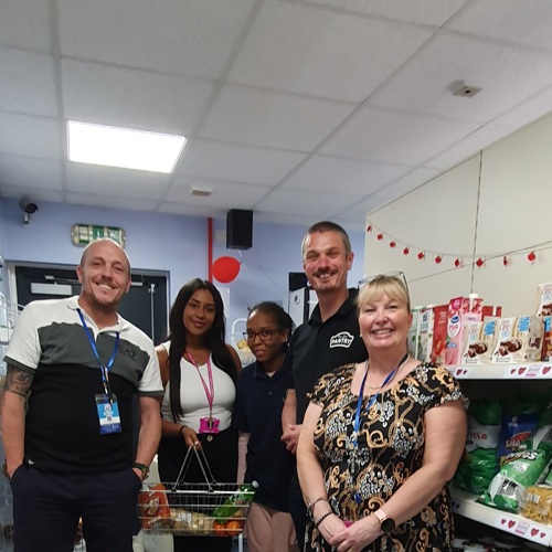 Some of the gteam at Whitby's Pantry in Preston with shelves stacked with food behinds