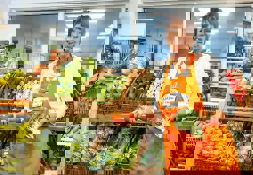 woman in orange apron with vegetables in hands