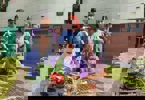 Group of children outside with vegetables on table 