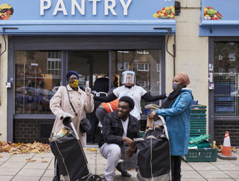 happy people in masks in front of blue pantry sign 