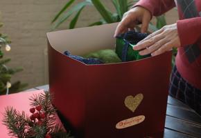 Hands placing a present into a red donation box