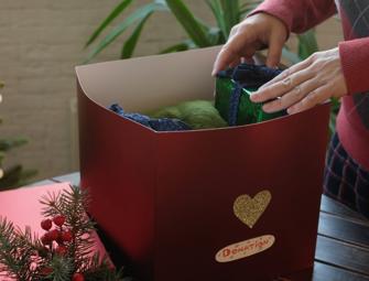 Hands placing a present into a red donation box