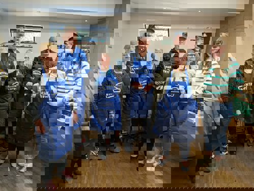 A group of men and ladies in Pantry aprons smiling