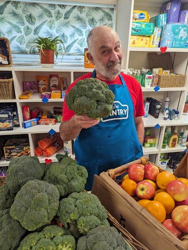 man holding up broccoli in blue apron