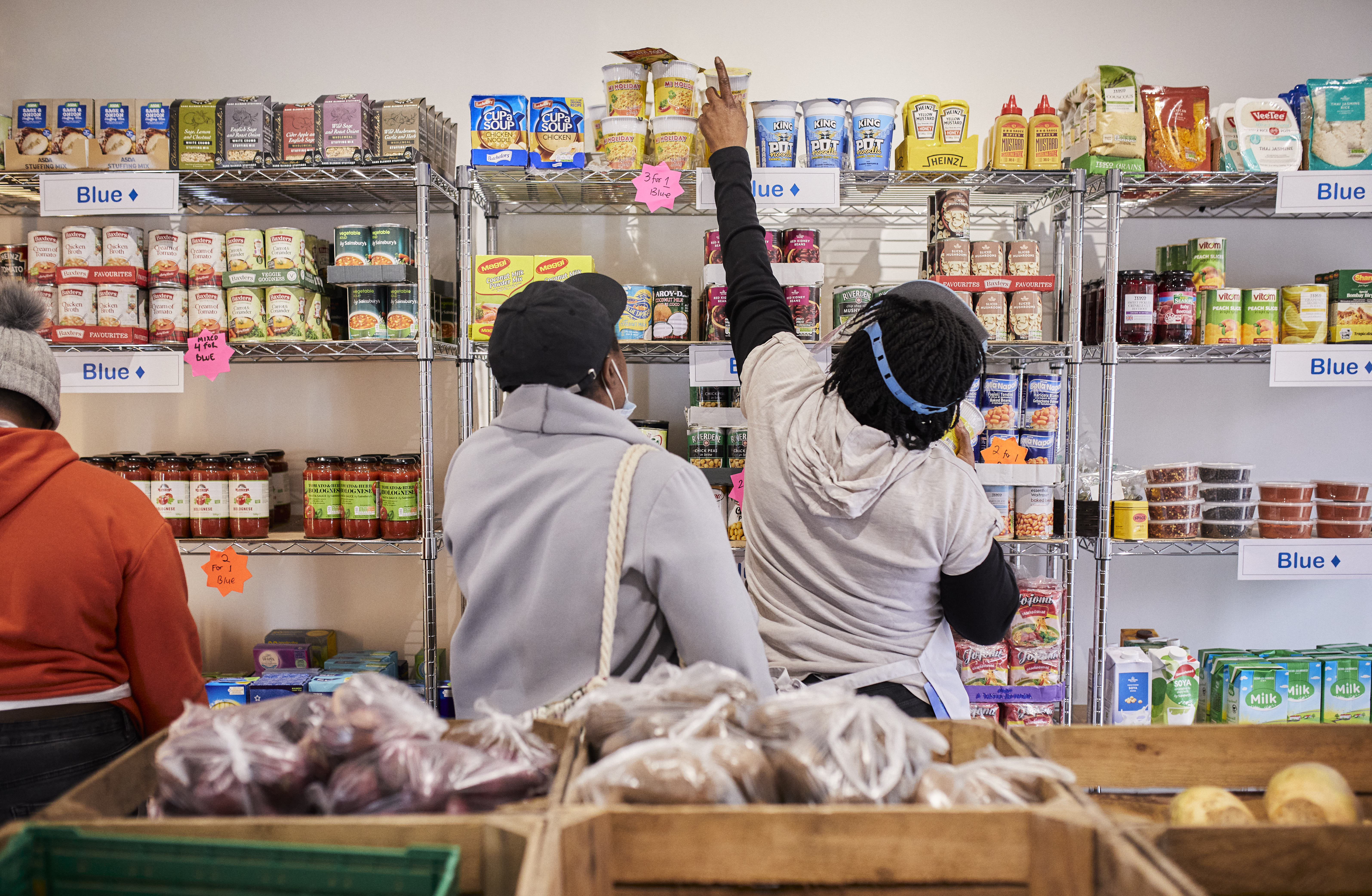 Pantry volunteer reaching to a high shelf to get food for a member