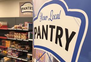 close up of local pantry logo on banner next to food shelves
