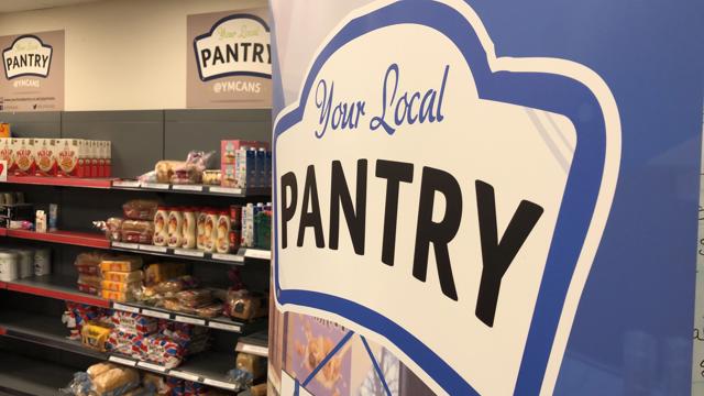 close up of local pantry logo on banner next to food shelves