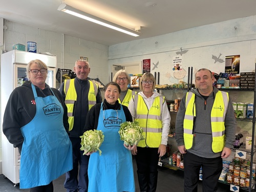 A group of men and women, some in yellow high viz and some in Pantry aprons