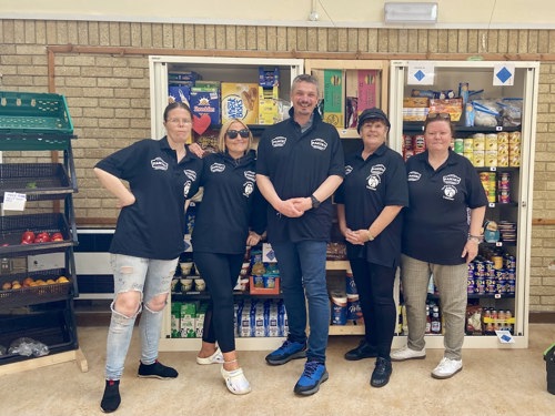 Pantry team in front of shelves stocked with food