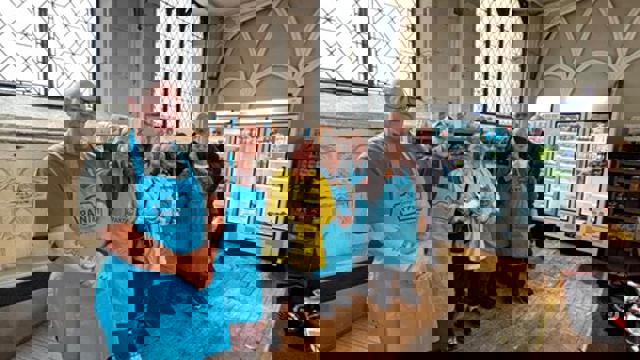 group in blue aprons and yellow coat in front of freezers