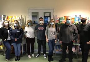 group of people in masks in front of food shelves