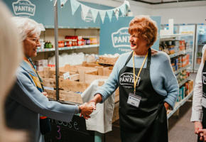 Woman holding a hand of another woman within a pantry
