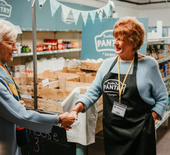 Woman holding a hand of another woman within a pantry