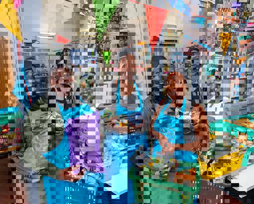 Group of woman holding up food with one holding a basket