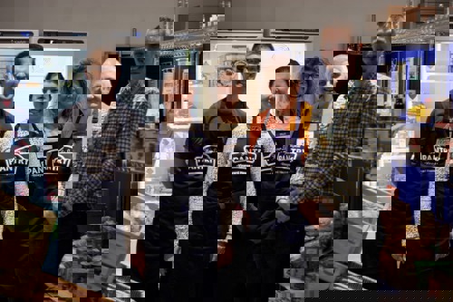 Men and women standing together in Pantry aprons in front of a fridge and freezer