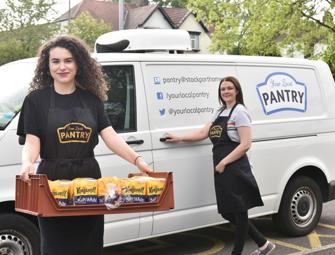 two woman outside of a your local pantry van with one holding a food tray with bread