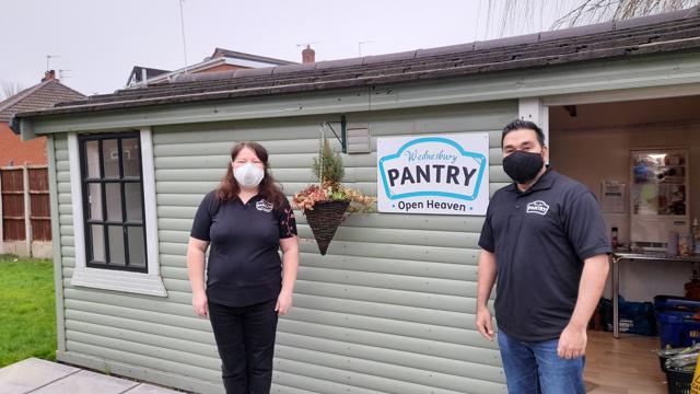 Woman and man in black shirt in front of pantry shed